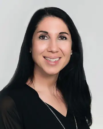 Francine Manfredi, smiling, in a black top against a pale grey background.